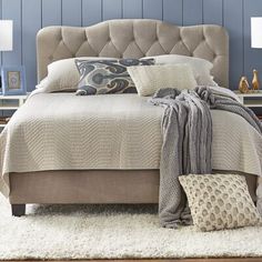 a large bed sitting on top of a white rug next to two tables and lamps