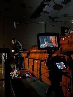 a man standing in front of an empty auditorium watching something on the floor with a video camera next to him