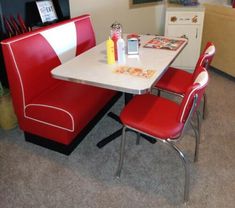 a kitchen table with two red chairs and a white counter top in front of it