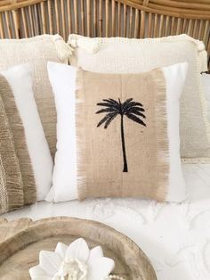 a pillow with a palm tree on it sitting on top of a bed next to a tray