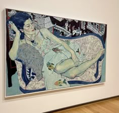 a woman laying on top of a couch next to a painting