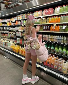 a woman is shopping in a grocery store and looking at the shelves full of juices