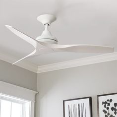 a white ceiling fan mounted on the side of a wall in a room with two framed pictures