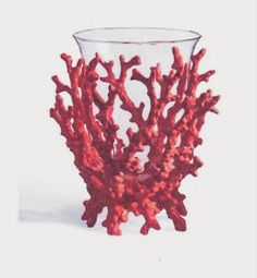 a red coral shaped vase sitting on top of a table