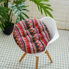 a chair cushion sitting on top of a white chair next to a potted plant