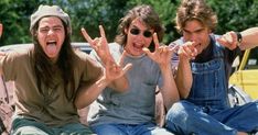 three young men sitting on the ground with their hands in the air and one holding his mouth open