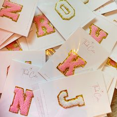 some pink and gold letters are on white cards