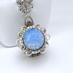 "Here is a unique handmade necklace featuring a multiple picture, 4 photo locket. Blue Czech art glass fire opal is set on a lacy filigree setting. Locket has the shape of a pocket watch, but springs open via the top latch to reveal four slots for photos. Perfect for showcasing multiple pictures of loved ones and family. Antique silver plated color. Locket itself measures 1\" wide. Total pendant length is 2\" long. Textured antique silver plated chain has a lobster style clasp and is pictured wi Blue Bohemian Jewelry With Locket, Blue Bohemian Locket Jewelry, Bohemian Blue Locket Jewelry, Unique Blue Medallion Jewelry, Blue Round Pendant Locket Jewelry, Locket Necklace Silver, Silver Locket Necklace, Picture Locket, Czech Art