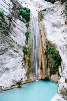 there is a small waterfall in the middle of this blue pool that's surrounded by large rocks