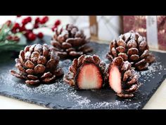 some pine cones are covered with powdered sugar and sit on a slate platter