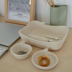 a laptop computer sitting on top of a desk next to two baskets filled with yarn