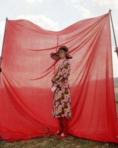 a woman standing in front of a red sheet