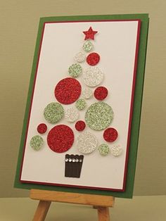 a christmas tree made out of buttons on a canvas with easel and papers around it