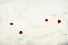 a white bowl filled with whipped cream and cherries on the rim, sitting on a table