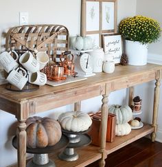 a wooden table topped with lots of white pumpkins and other decorations on top of it