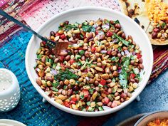 a white bowl filled with beans next to other dishes on a blue tablecloth and place mats