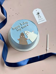 a birthday cake with an image of two dogs on it and a blue ribbon next to it