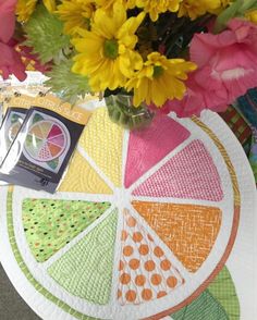 a vase filled with yellow and pink flowers on top of a table covered in paper