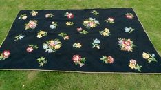 a black blanket with flowers on it laying in the grass