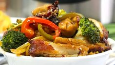 a white bowl filled with chicken, broccoli and peppers on top of a table