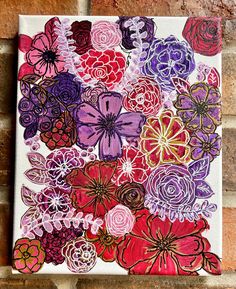 a painting with flowers painted on the side of a brick wall in purple, red and pink colors