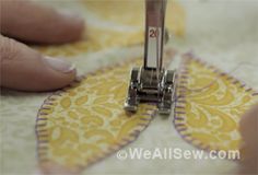 someone is sewing on a yellow and white quilt