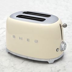 a cream colored toaster with the word smeg on it sitting on a marble surface