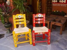 two brightly colored chairs sitting next to each other in front of a potted plant