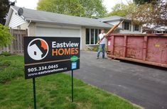 a man standing next to a dumpster in front of a house with a sign that says eastview homes