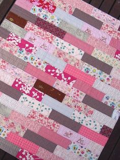 a pink and brown patchwork quilt sitting on top of a wooden table