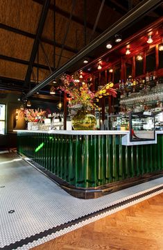 the interior of a bar with green and white tile on the floor, decorated with flowers