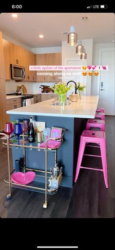 a kitchen island with pink stools next to it