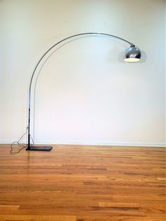 the floor lamp is on in an empty room with hard wood floors and white walls