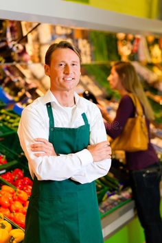 a man standing in front of a produce stand with his arms crossed and smiling at the camera