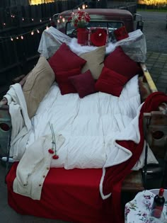 a bed with red and white pillows on it in the back of an old truck