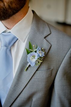 a man wearing a suit and tie with a boutonniere on his lapel