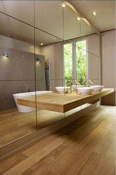 a bathroom with two sinks and mirrors on the wall next to each other in front of large windows