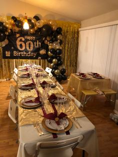 a table set up for a 60th birthday party with black, gold and silver balloons