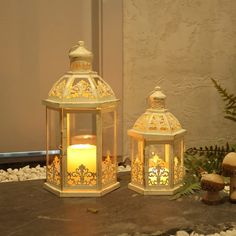 two lit candles sitting next to each other on top of a stone slab in front of a wall