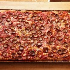 a pizza with pepperoni and cheese in a pan on top of a wooden table