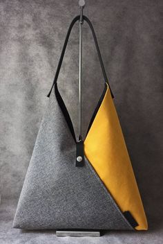 a grey and yellow bag hanging from a hook on a gray wall with a black handle