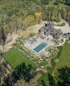 an aerial view of a large house with a soccer field in the foreground and tennis court on the far side