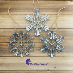 three metal snowflakes hanging from string on wooden surface