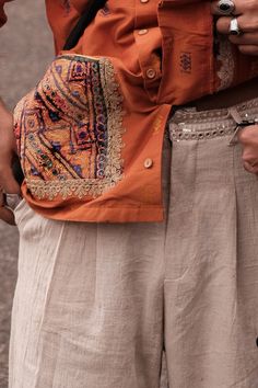 White cotton pants adorned with silver silk thread and mirror embellishments, Gota, traditionally used in South Asian festive outfits. These pants feature a formal pleated fit with a wide bottom and hand-embroidered waistband adorned with a row of stitched mirrors. Luxury Resham Embroidered Pants With Traditional Drape, Festive Embroidered Chanderi Pants, Traditional Semi-stitched Embroidered Pants, Traditional Embroidered Silk Pants, Embroidered Chanderi Pant Set, White Cotton Pants, Festive Outfits, Silver Silk, South Asian