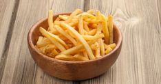 a wooden bowl filled with french fries on top of a table