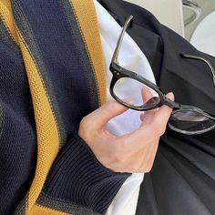 a person wearing glasses while sitting down with their hand on the arm of another persons shoulder