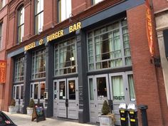 the front of a restaurant with large windows and doors on it's side walk