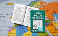 the sudoku puzzles travel size book is open on a world map and it's contents are laid out