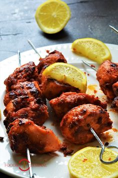 chicken skewers with lemon wedges on a white plate, ready to be eaten