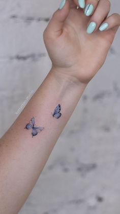 a woman's arm with two blue butterflies on the left side of her arm